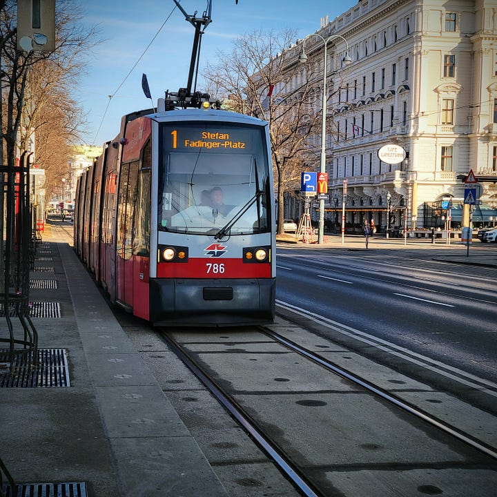 Two photos of transit in Vienna. First photo: A woman rides a fat-tire ebike along a bike path. Second photo: A red and gray streetcar along Vienna's ring street.