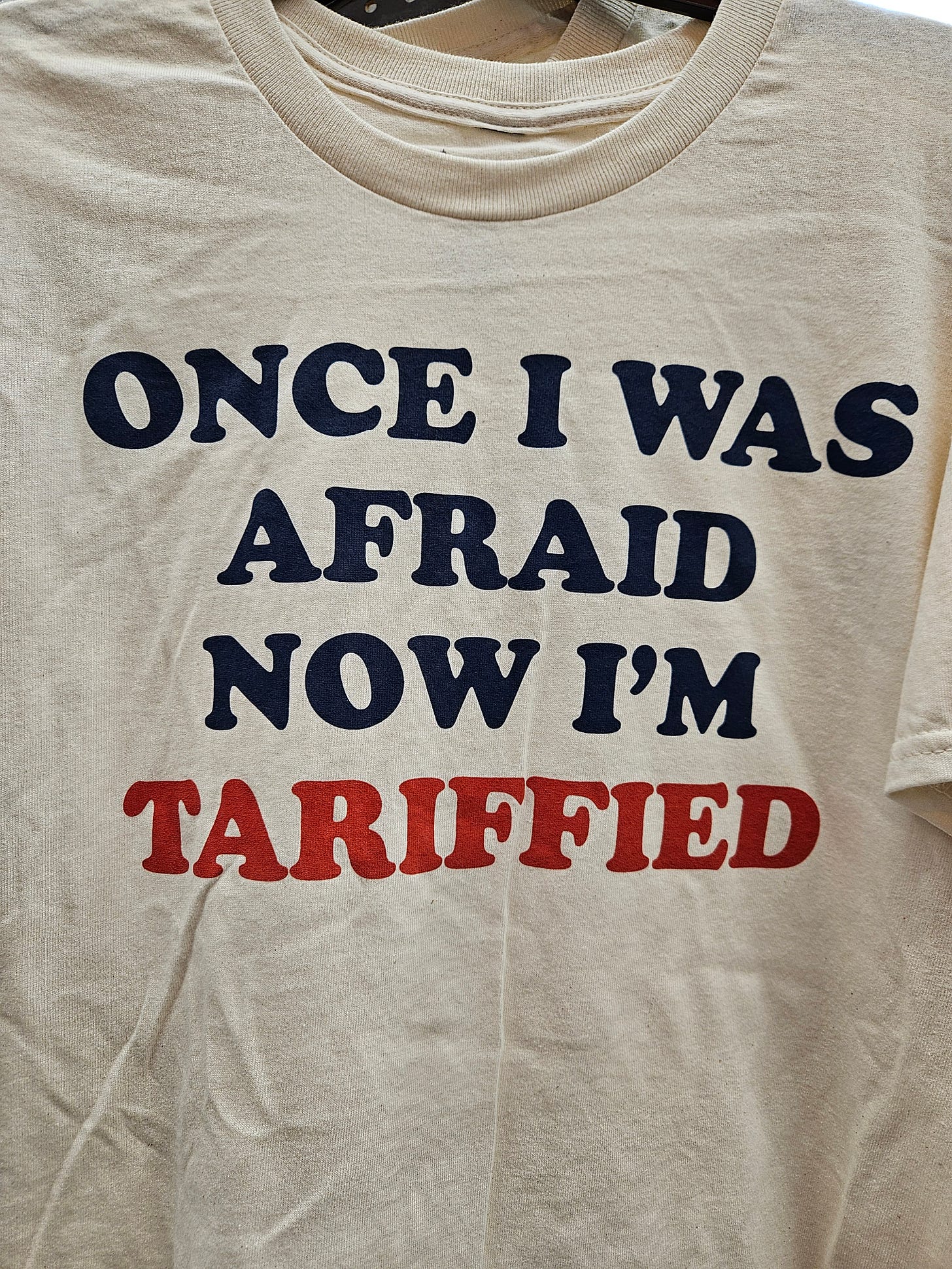 A white t-shirt that says, "Once I was afraid now I'm tariffied."