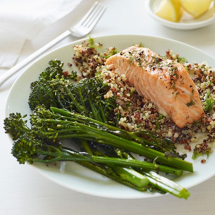 This may contain: a white plate topped with salmon and broccoli covered in seasoning next to lemon wedges This may contain: a white plate topped with salmon and broccoli covered in seasoning next to lemon wedges