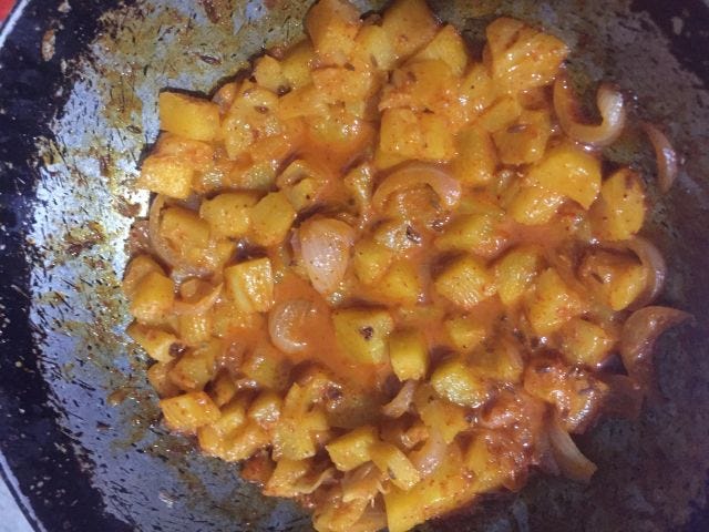 A kadai with pineapple and onions in a coconut milk broth