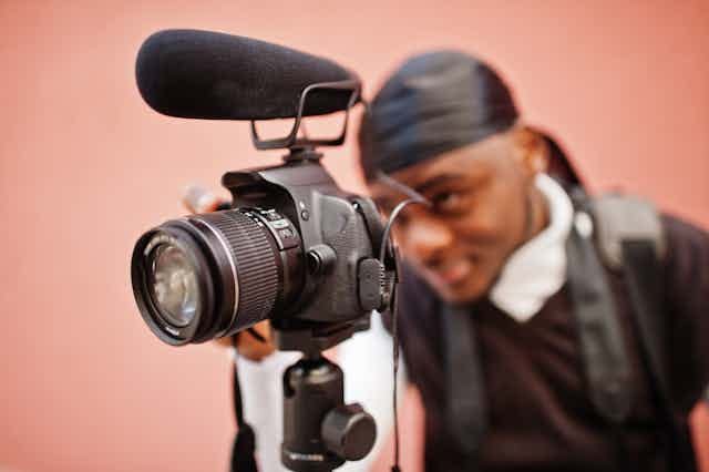 A close-up photograph of a young man using a film camera