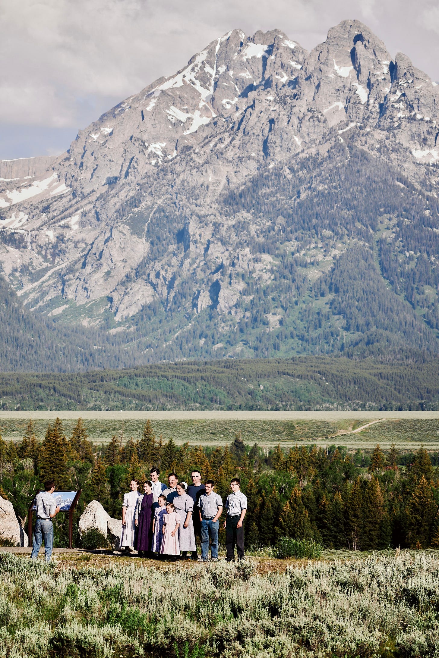 A religious group takes a group photo in front of Grand Teton National Park