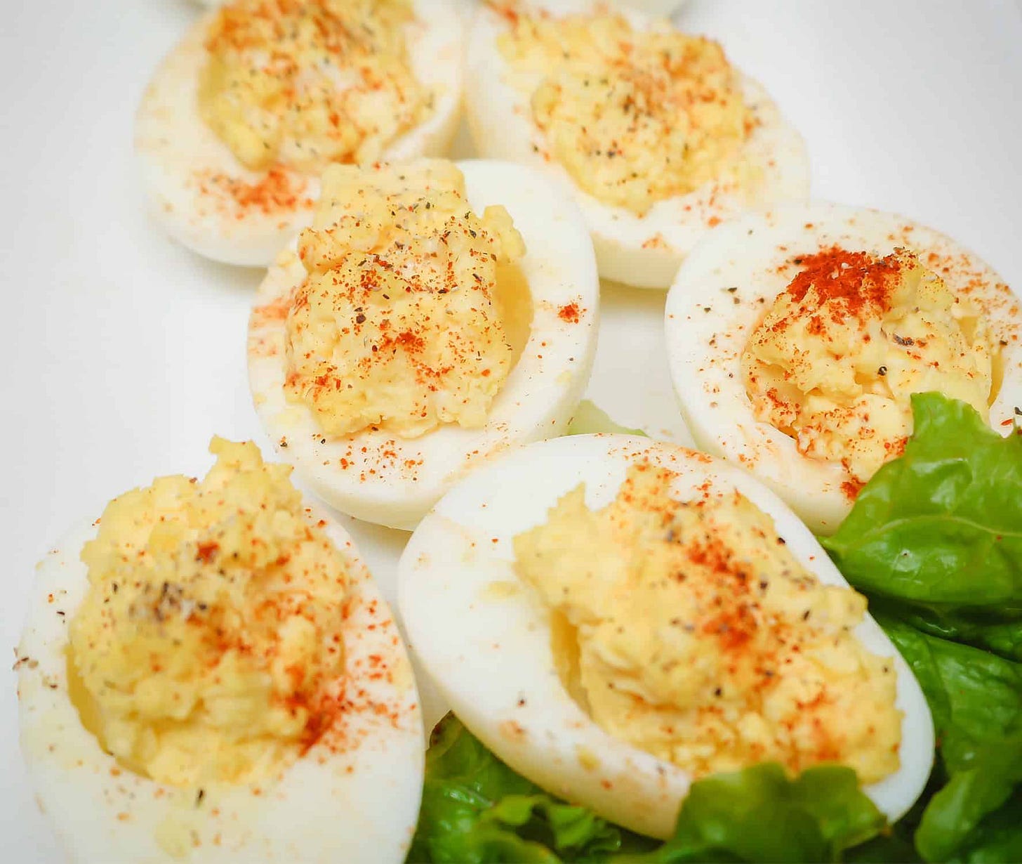 Close-up of soul food deviled eggs with creamy yolk filling, paprika seasoning, and lettuce garnish, a classic Southern Easter recipe by The Soul Food Pot®