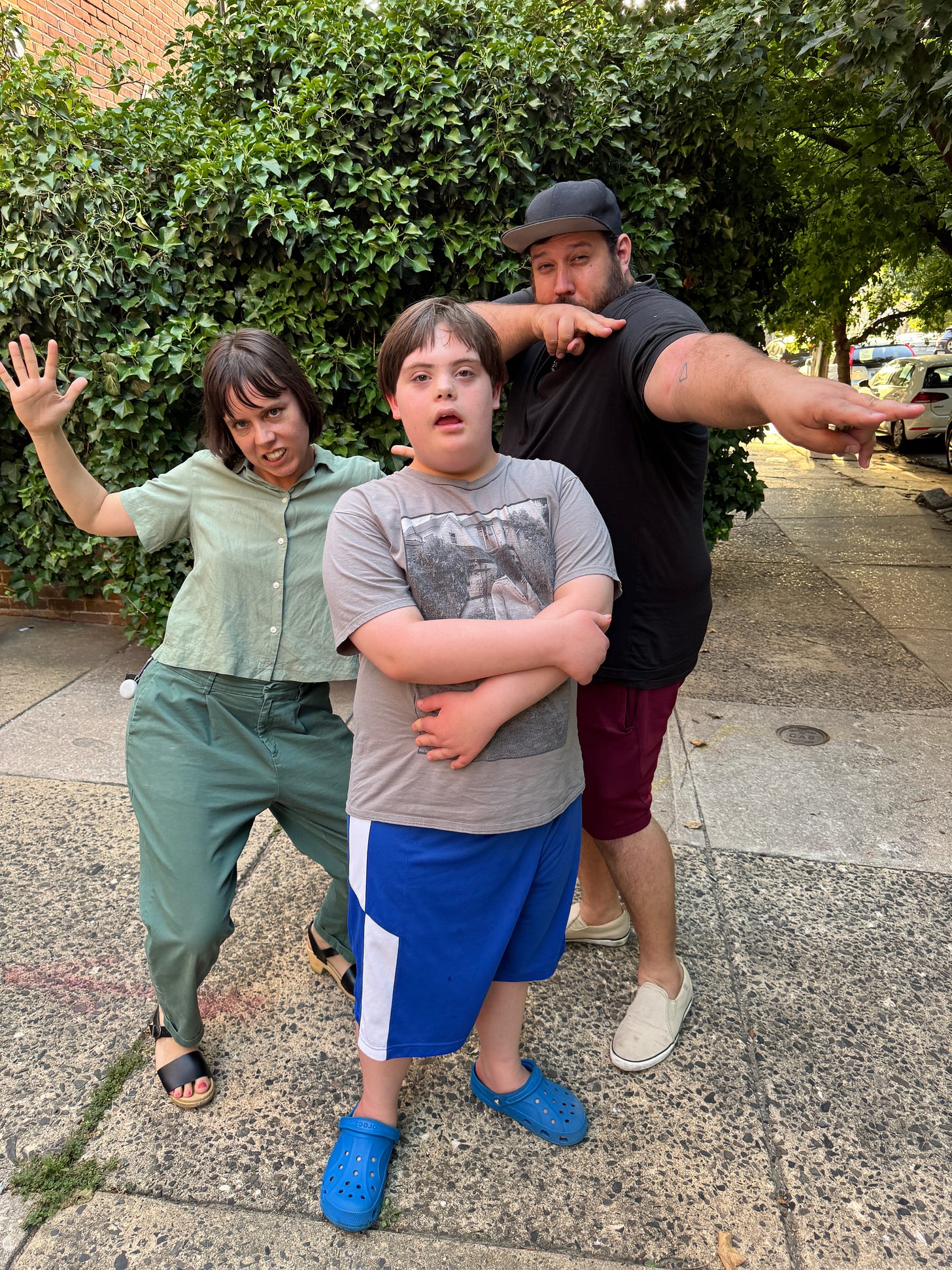 Three white people stand in poses, their limbs askew.