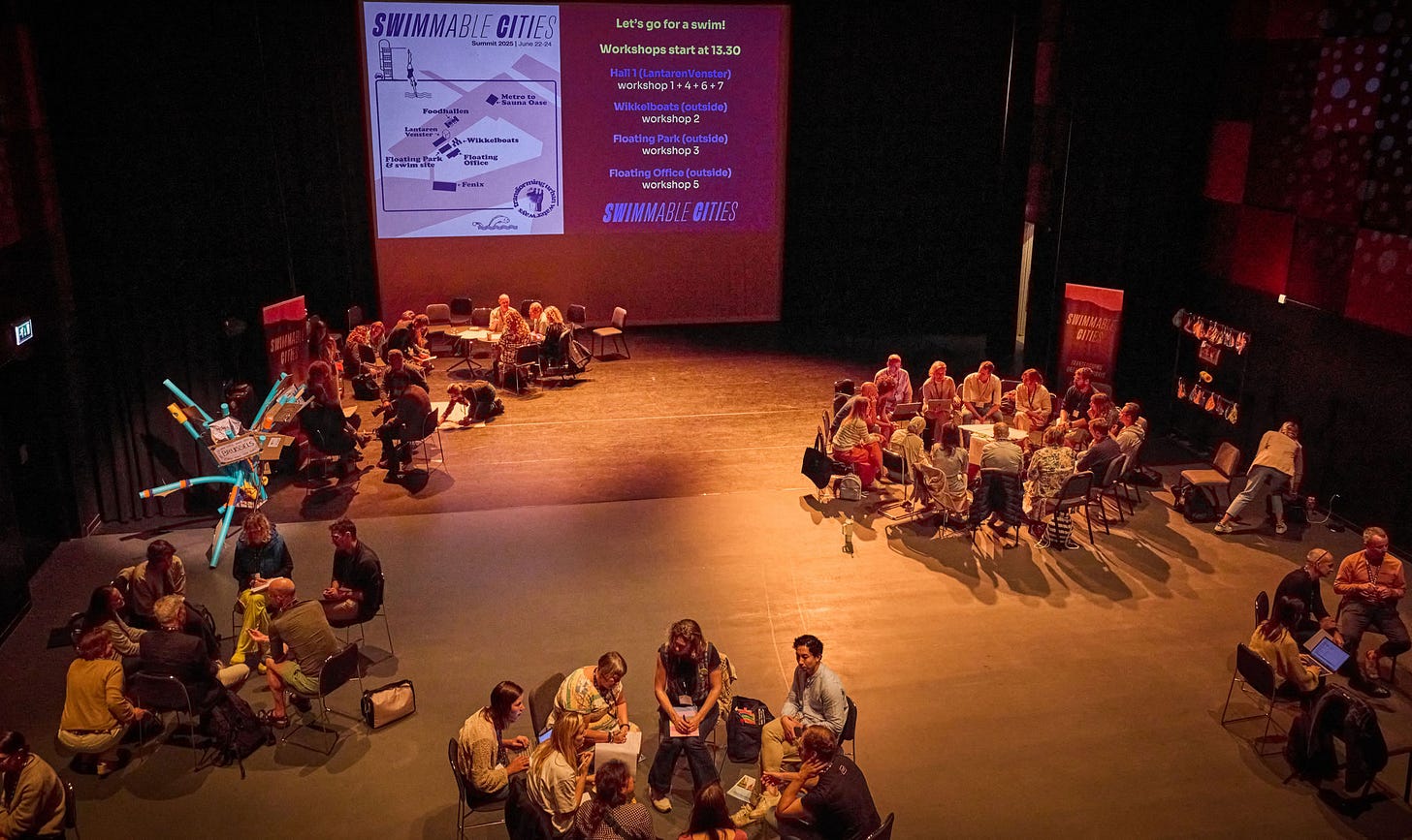 Groups of people discuss in circles in a low-lit conference presentation room