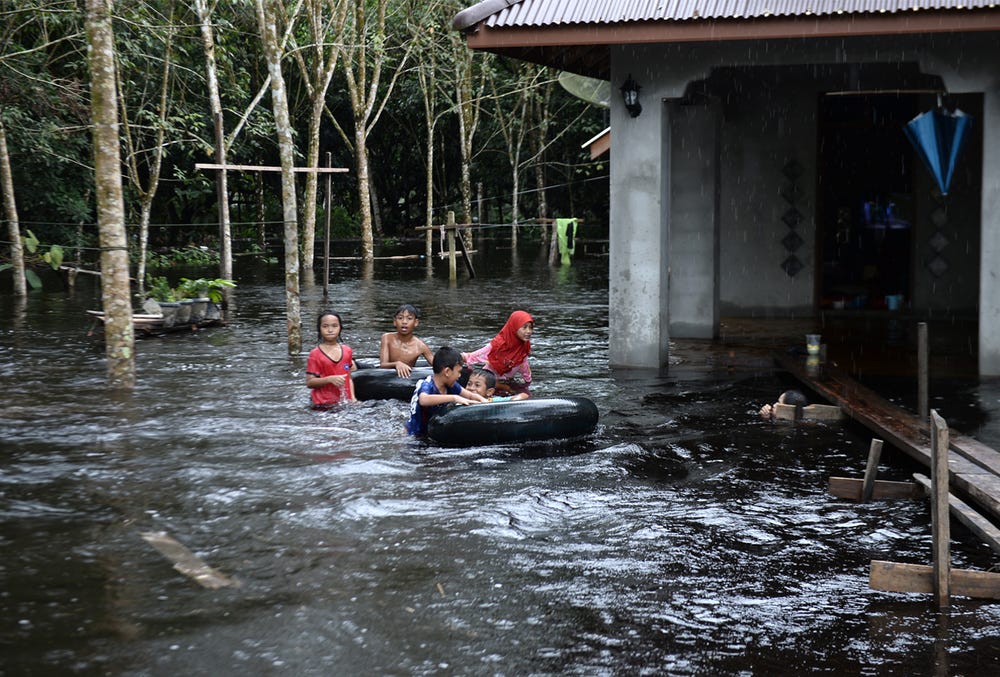 Children play outside a house affected by floodwaters following heavy rains in southern Thai province of Narathiwat on 2 December 2019. Children play outside a house affected by floodwaters following heavy rains in southern Thai province of Narathiwat on 2 December 2019.