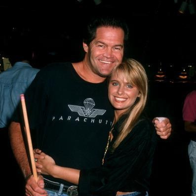 This may contain: a man and woman hugging each other with a pool cue in their hand at a party
