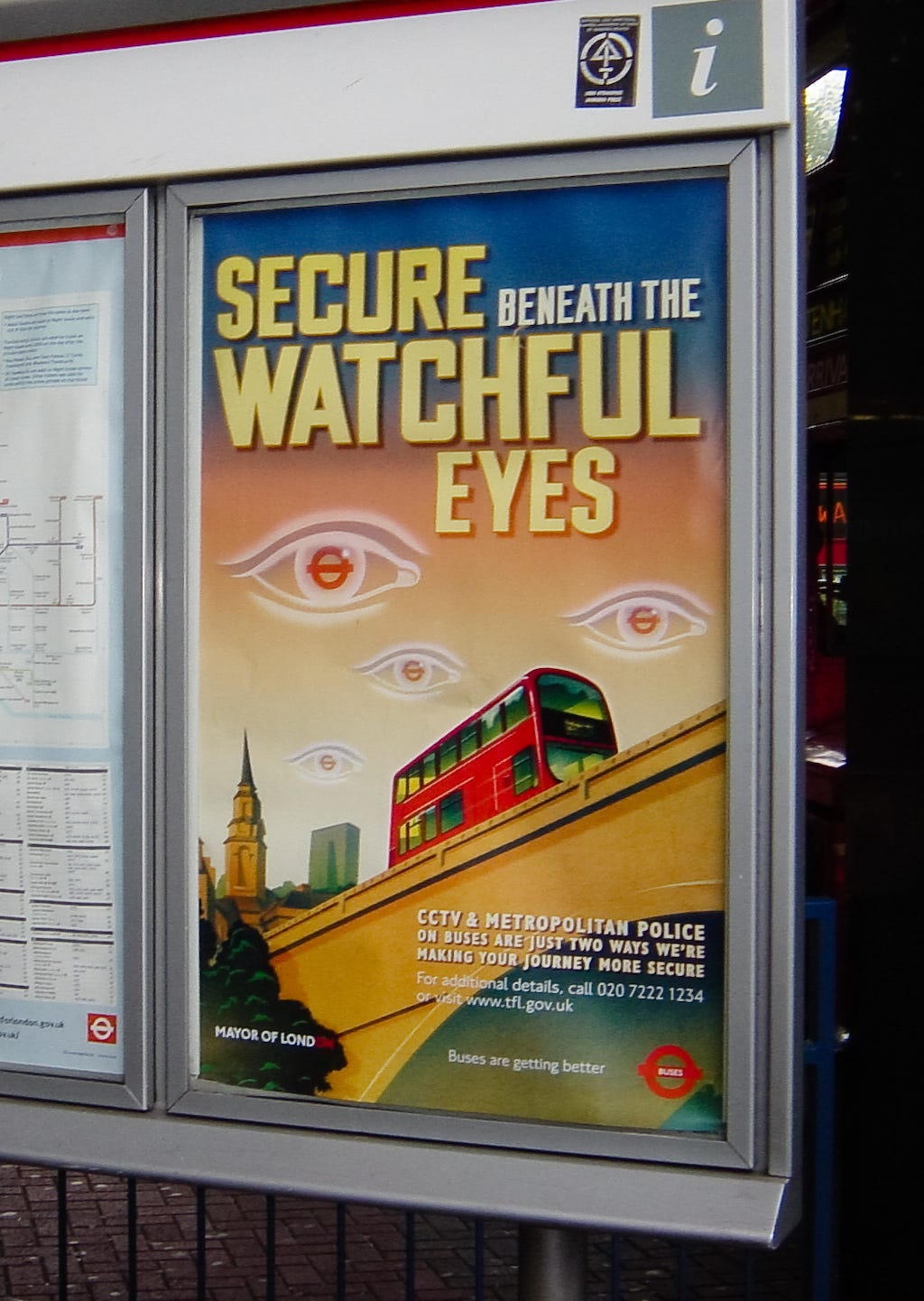 A poster in the London public transit system. The poster reassures bus riders that they are “secure beneath the watchful eyes.” A poster in the London public transit system. The poster reassures bus riders that they are “secure beneath the watchful eyes.”