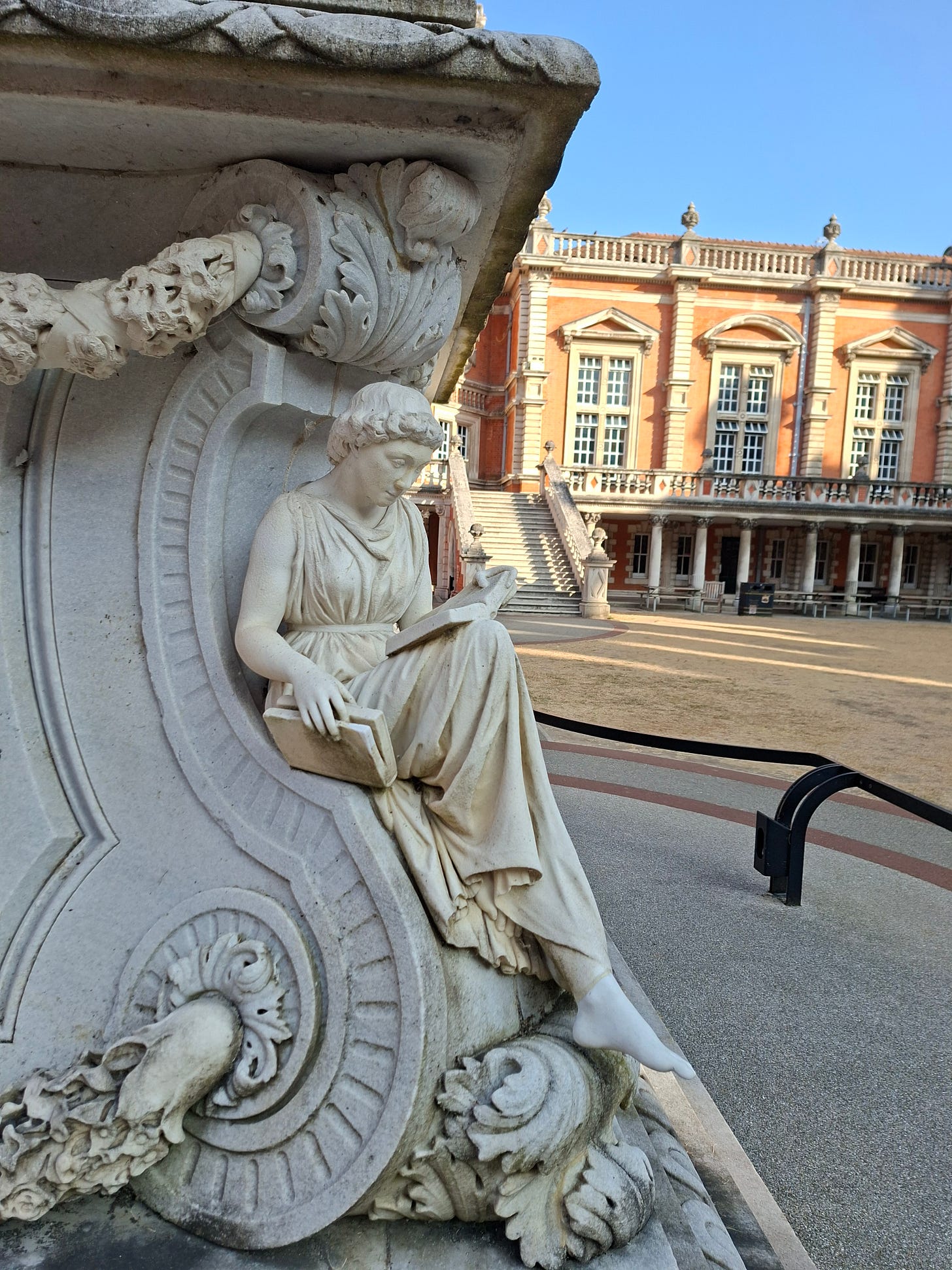 marble statue of a woman reading multiple paperbacks