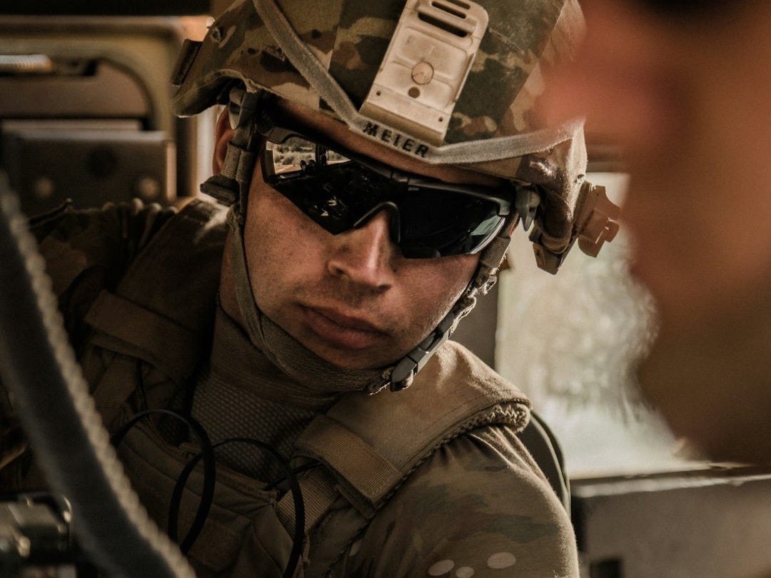 man in black and brown camouflage jacket wearing black sunglasses