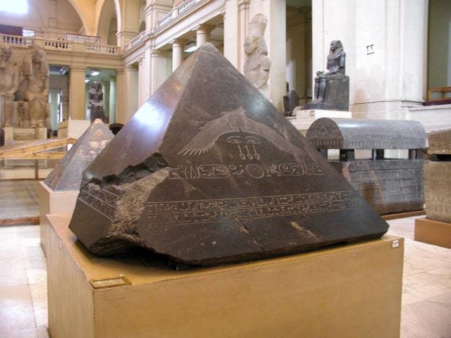 This may contain: a large rock with writing on it in a room filled with statues and other items