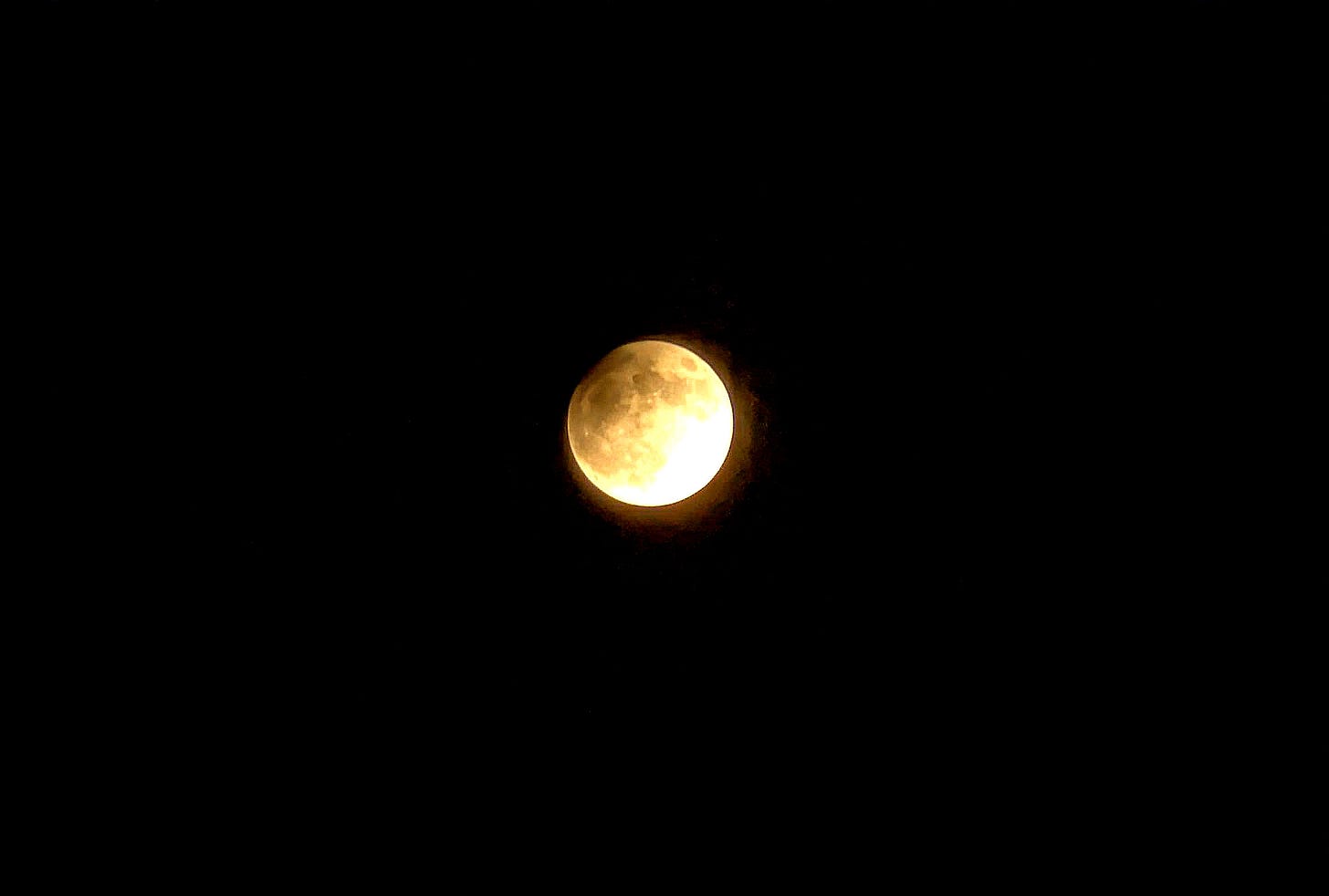 A picture of the Pisces Full Moon and Partial Lunar Eclipse, with a shadow creeping across half of an otherwise brilliantly shining moon.