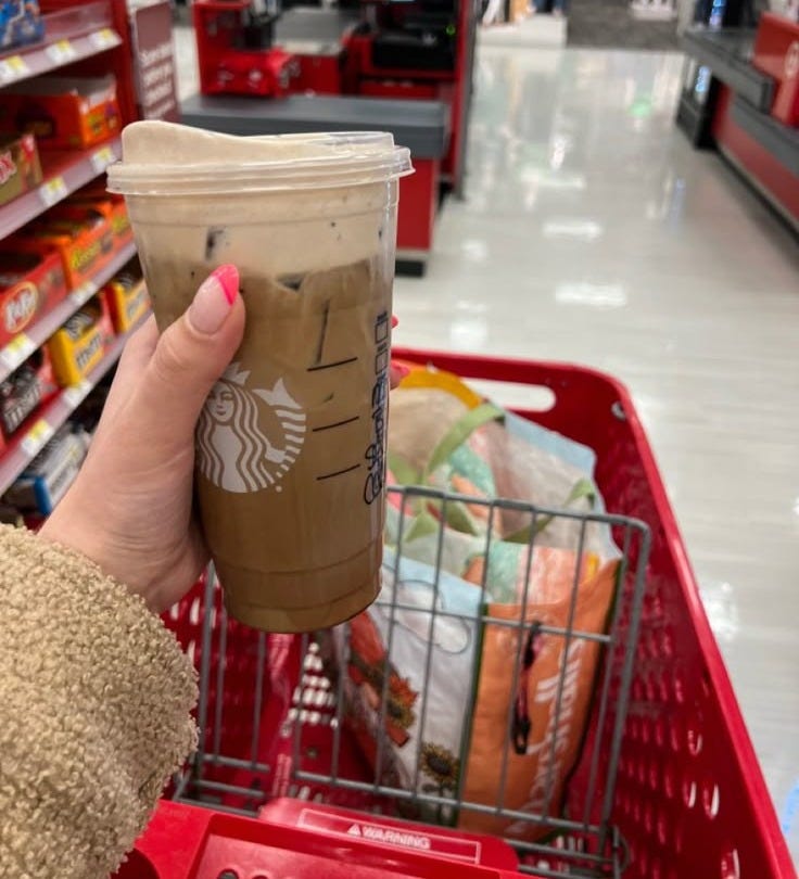 This may contain: a woman is holding a starbucks cup in her hand while shopping at the grocery store