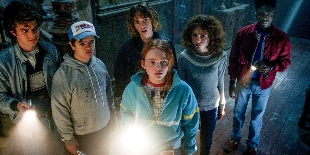 The Hawkins kids gather around a flashlight in Stranger Things Season Four