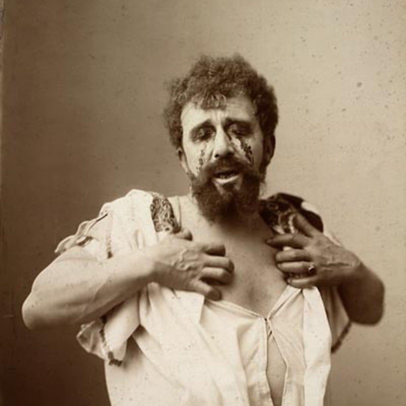 A stage actor as Oedipus, blood on his face, holding open his torn shirt A stage actor as Oedipus, blood on his face, holding open his torn shirt