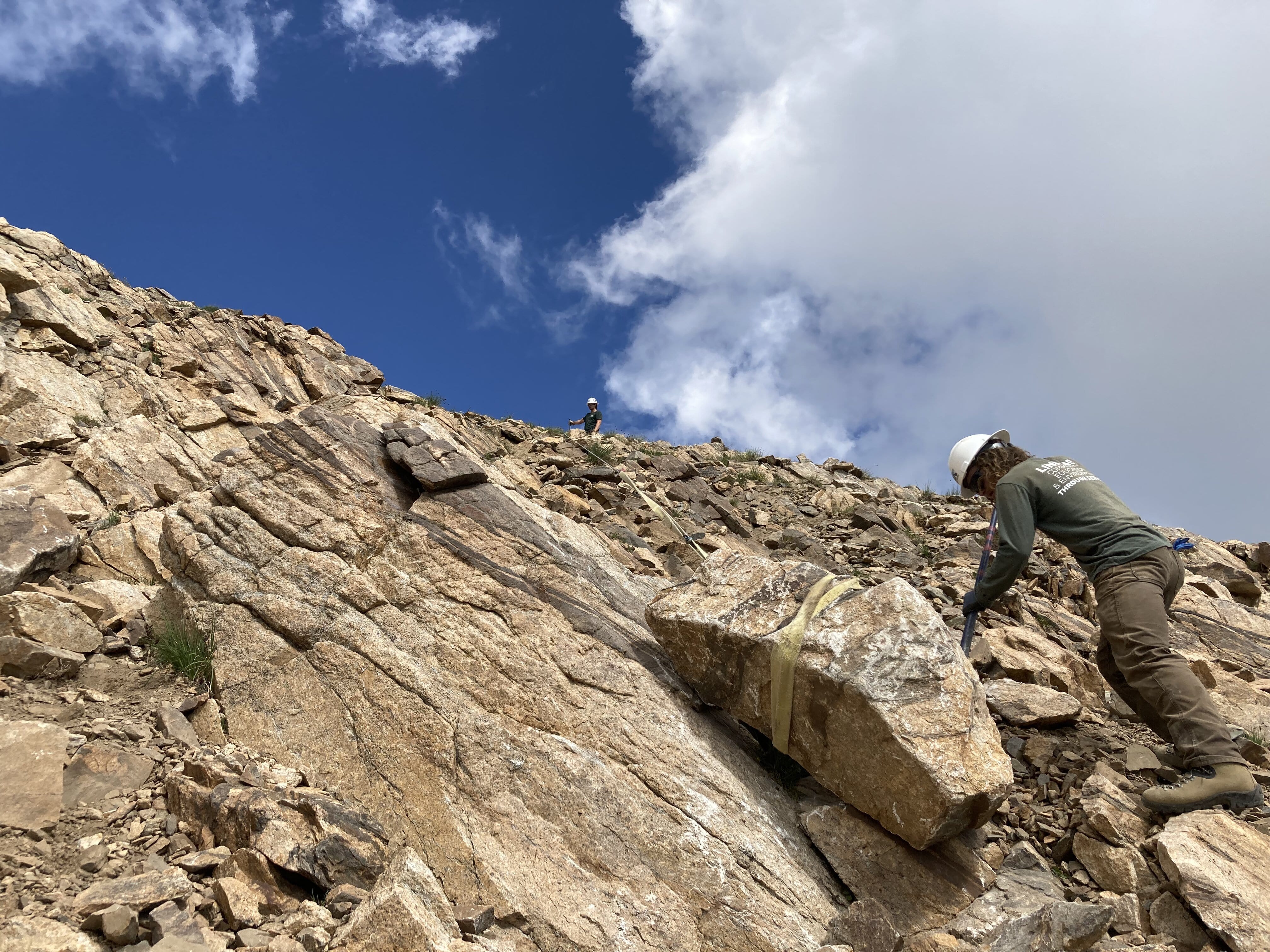 Two CFI volunteers work to move a large rock into position on a trail build