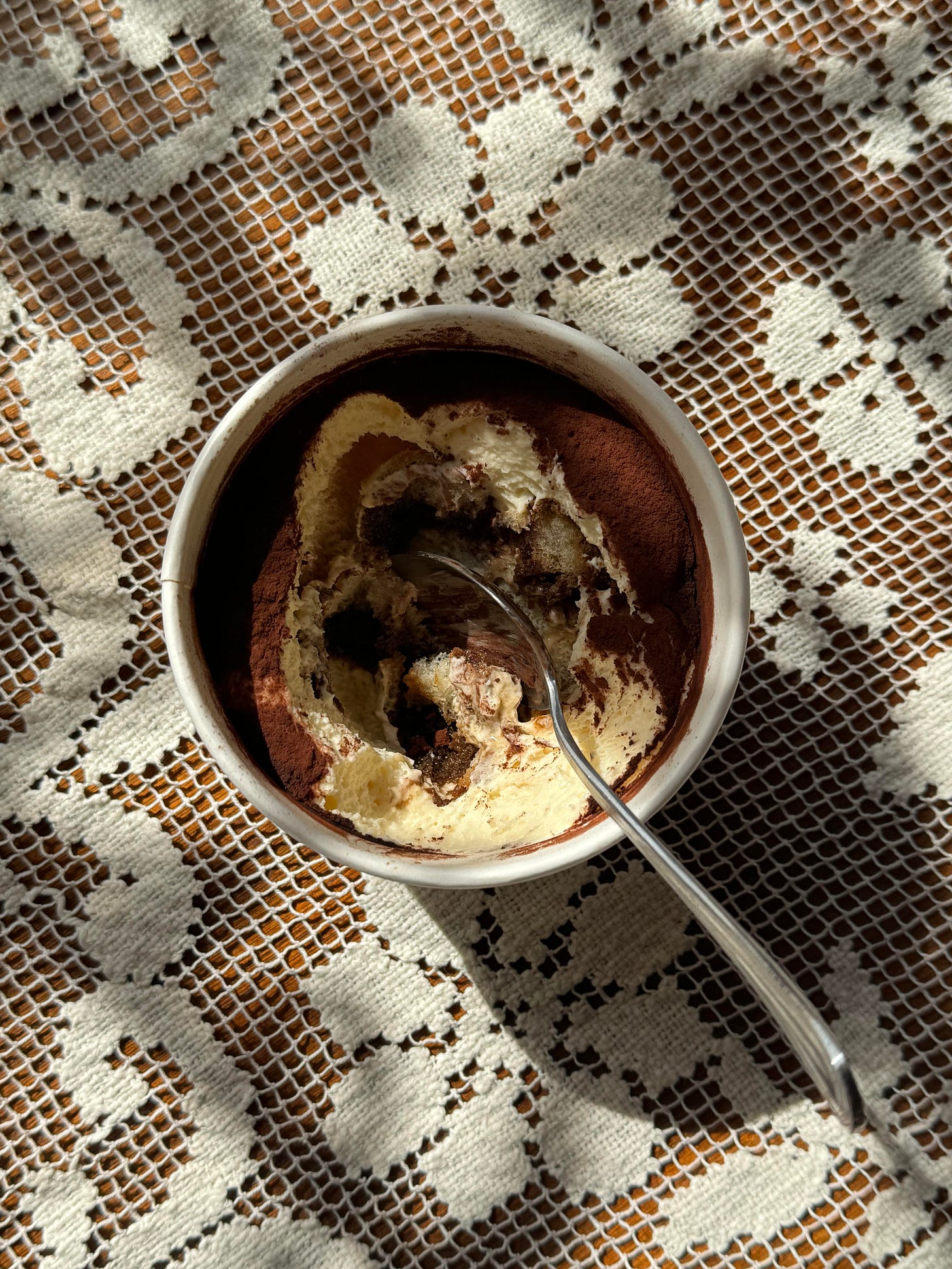 A single serving of tiramisu, partly eaten.