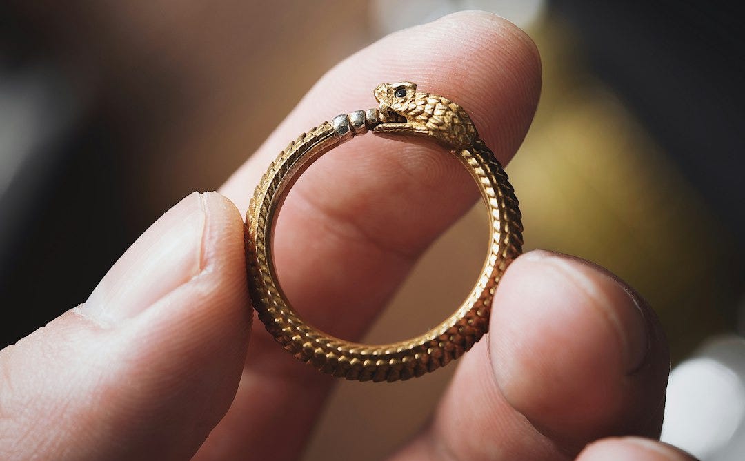 a person holding a gold ring in their hand