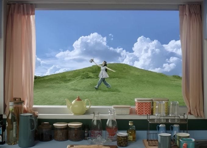 This may contain: a woman standing in front of a window with an image of a green hill behind her