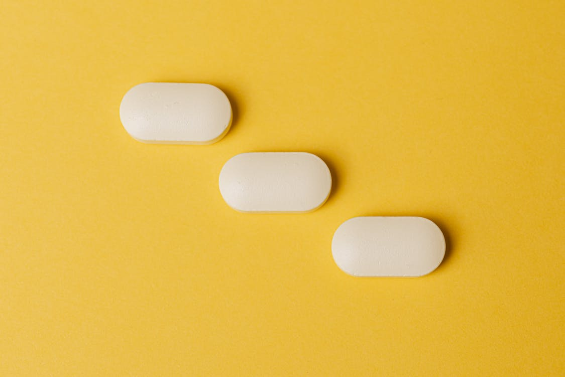 Free Set of pills on yellow surface Stock Photo