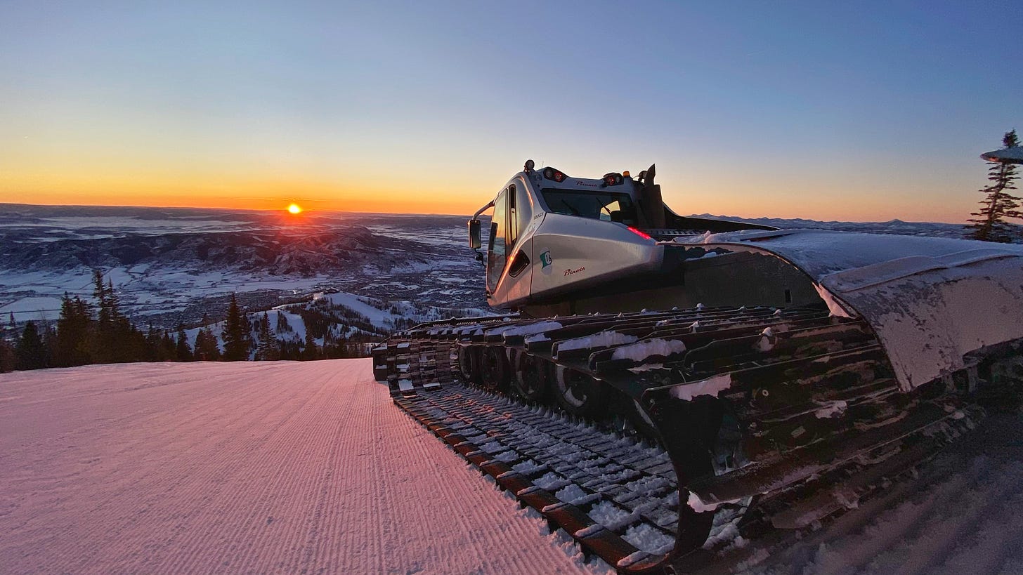 Photo of a snow groomer parked and overlooking the Yampa Valley at sunset.