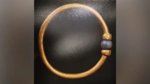 Egyptian Ministry of Tourism and Antiquities The bracelet is gold and adorned with a blue, round bead