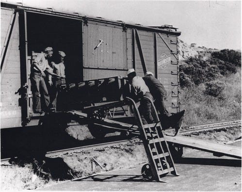 A group of men loading a train

Description automatically generated