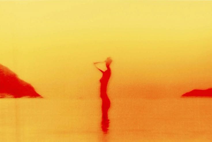 This may contain: a person standing in the water with an umbrella over their head and holding a frisbee