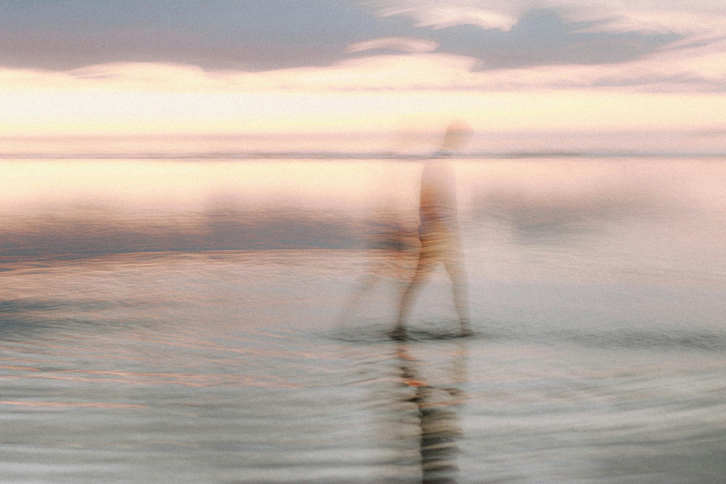 A serene and artistic blur of a silhouette walking on the shore at sunset, evoking tranquility and calm