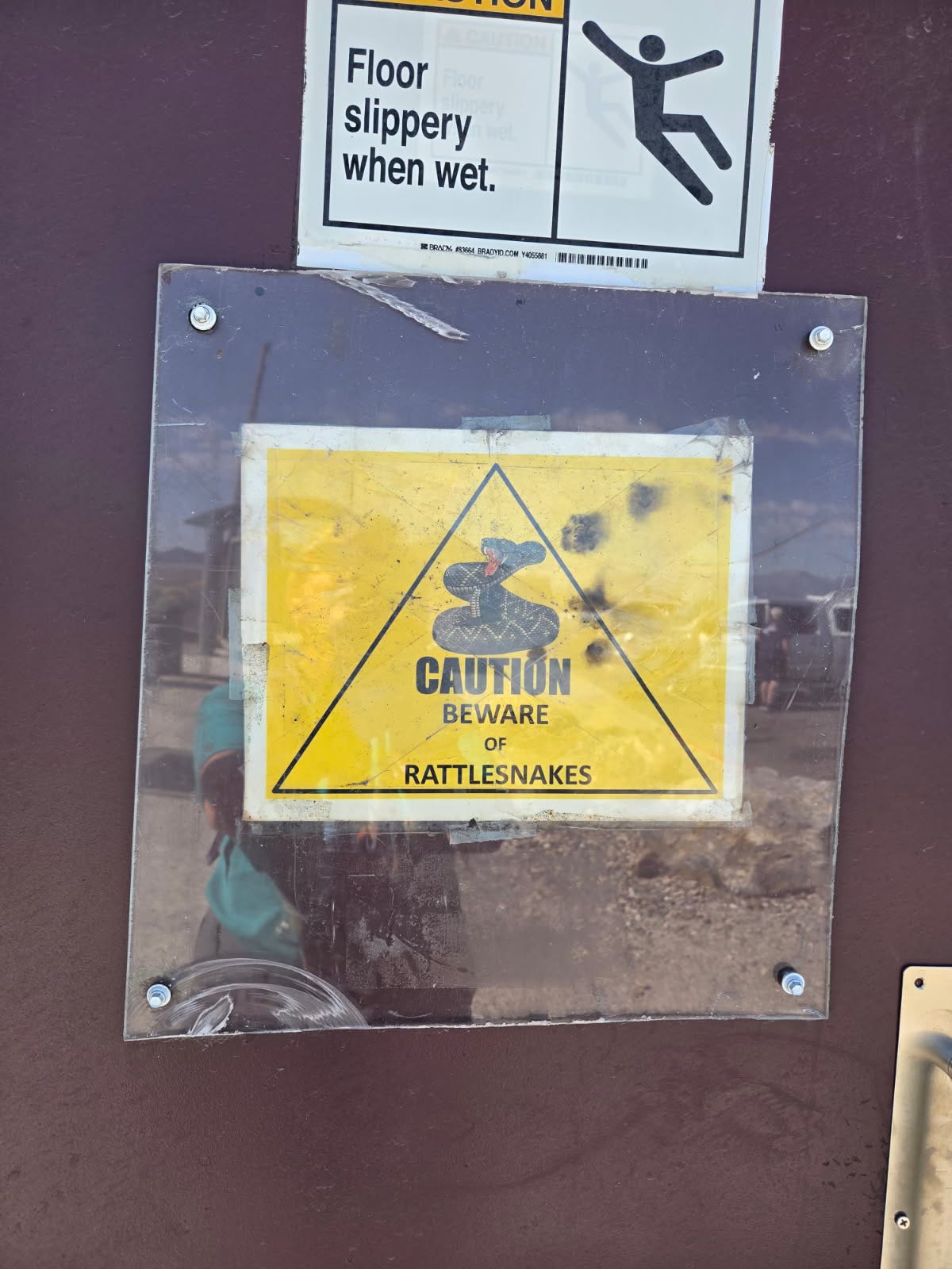 A brown door with a yellow sign that reads, “CAUTION. Beware of rattlesnakes.”