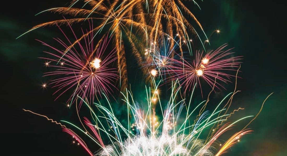 A night sky with orange, purple, and green fireworks A night sky with orange, purple, and green fireworks