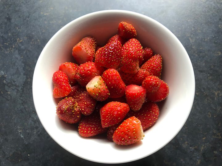 A bowl of strawberries, pastry on floor, a fruit flan