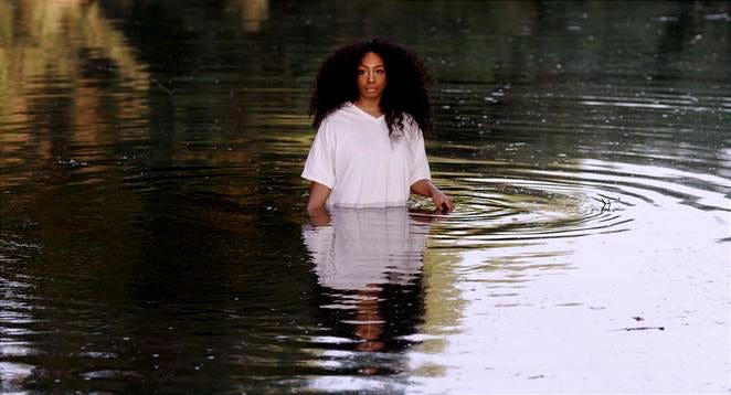This may contain: a woman standing in the middle of a body of water