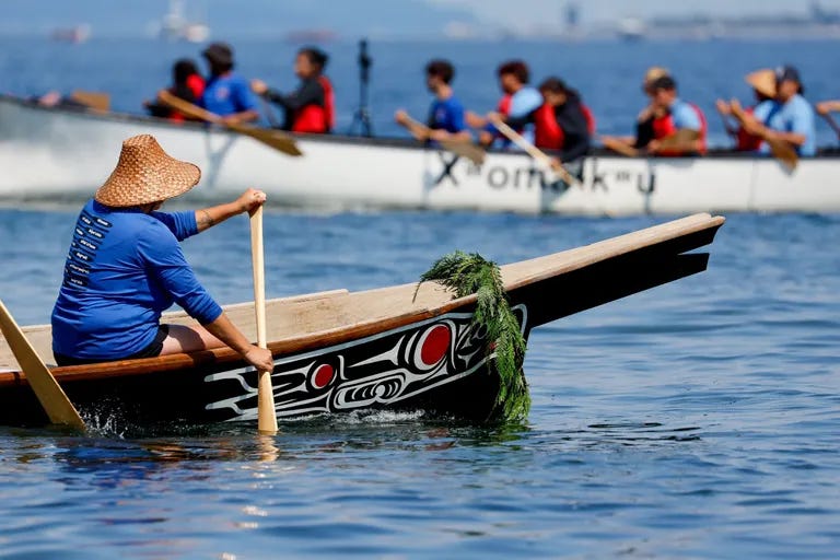 Canoes cross each other’s paths as the families wait to come into shore during the last leg of the 2023 canoe journey. (Jennifer Buchanan / The Seattle Times)