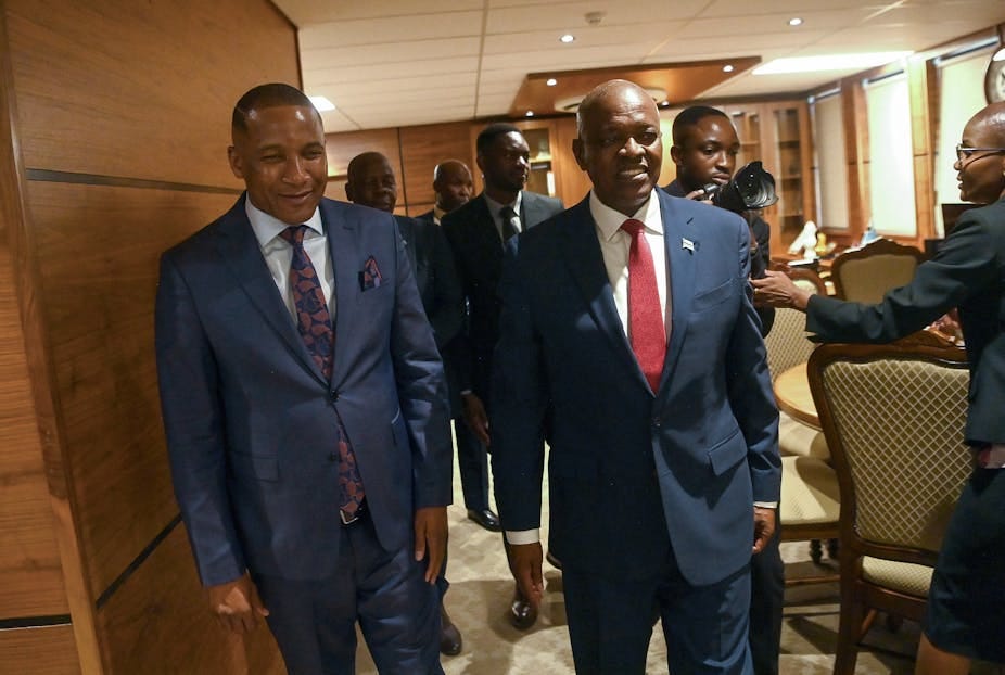Two men wearing suits and ties walk in an office. Two men wearing suits and ties walk in an office.
