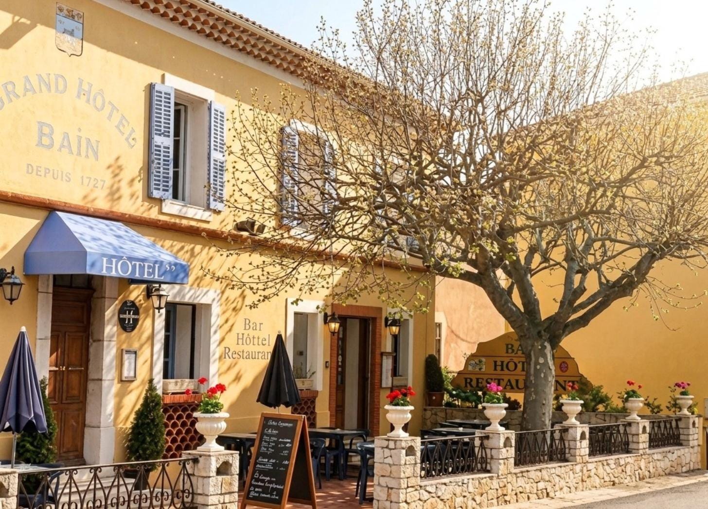 Grand Hôtel Bain exterior, Comps-sur-Artuby, Provence. Yellow facade with "Depuis 1727" painted on the wall. Grand Hôtel Bain exterior, Comps-sur-Artuby, Provence. Yellow facade with "Depuis 1727" painted on the wall.