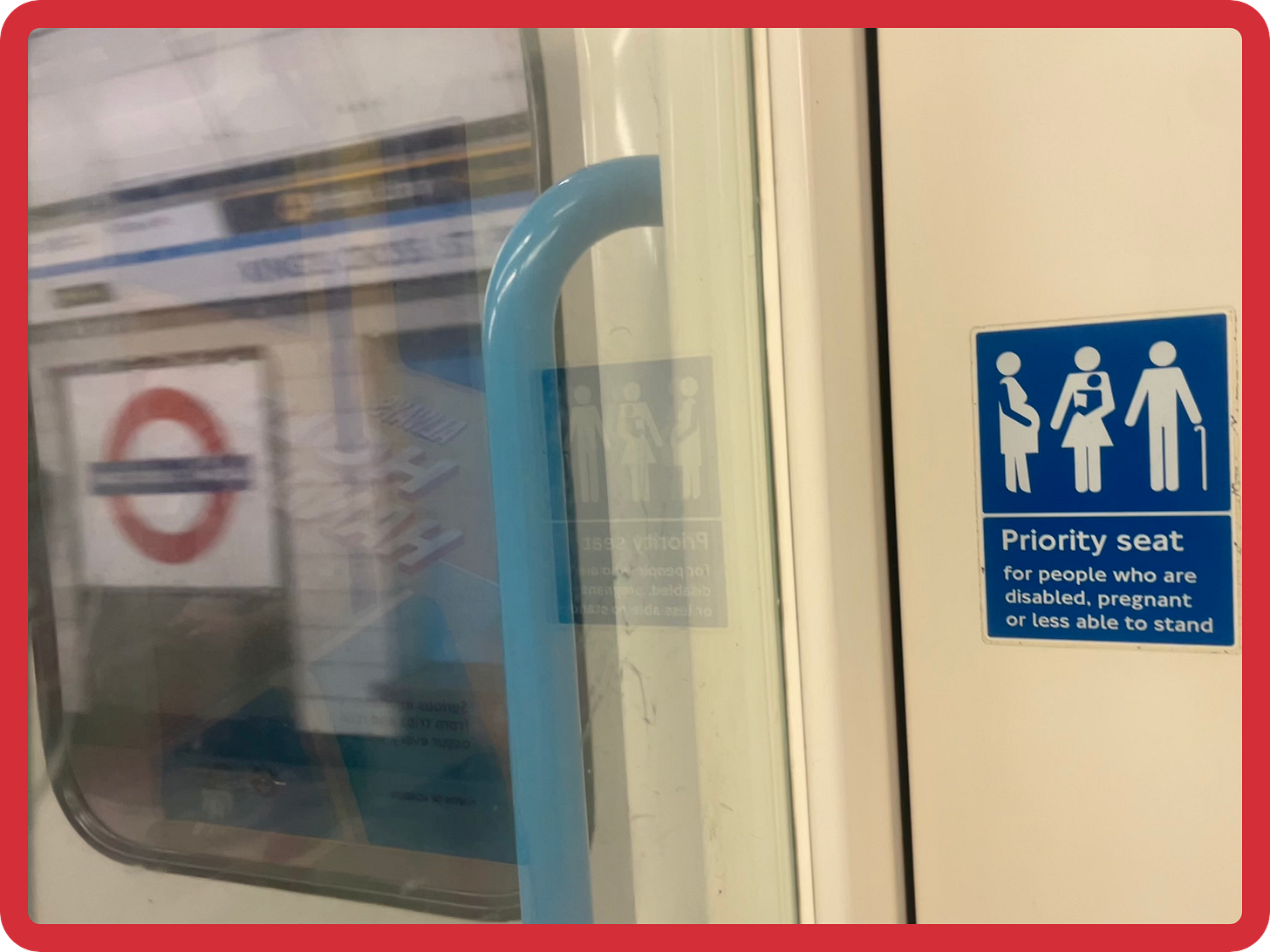 A photo of a priority seat sign on the Tube. The sign reads "Priority seat for people who are disabled, pregnant or less able to stand." and features stick figures who are pregnant or holding a walking stick. To the left of the sign, through the window, there is a blurry, in-motion view of the Victoria Line platform at King's Cross, with a big blue and red Tube sign. A photo of a priority seat sign on the Tube. The sign reads "Priority seat for people who are disabled, pregnant or less able to stand." and features stick figures who are pregnant or holding a walking stick. To the left of the sign, through the window, there is a blurry, in-motion view of the Victoria Line platform at King's Cross, with a big blue and red Tube sign.