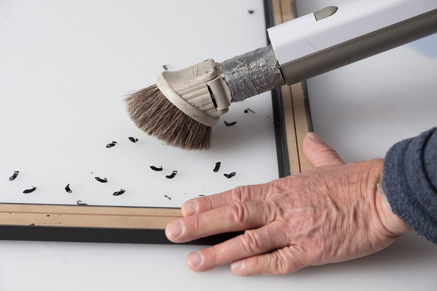 vacuuming and brushing a framed print prior to final assembly