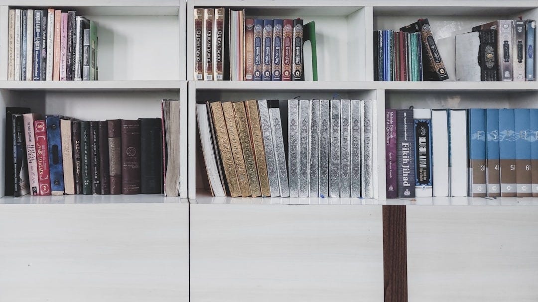 a bookshelf filled with lots of books on top of white shelves a bookshelf filled with lots of books on top of white shelves