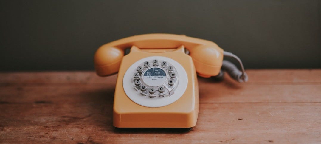 brown rotary dial telephone in gray painted room