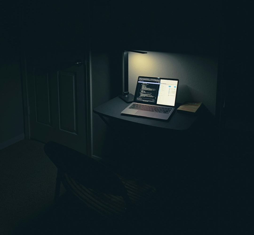 a laptop computer sitting on top of a desk in a dark room