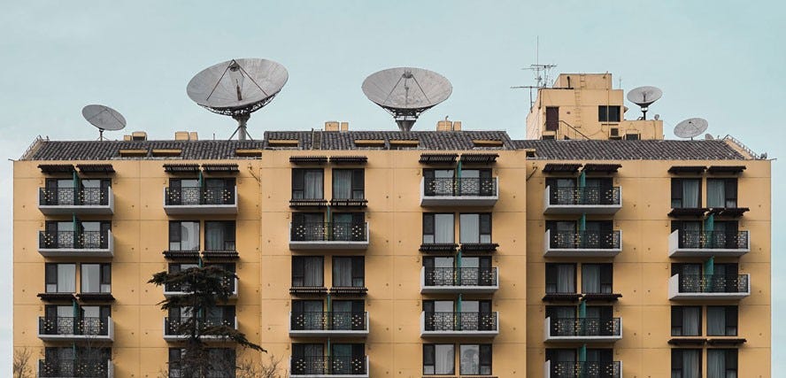 tan apartment complex with black windows and service dishes on roof