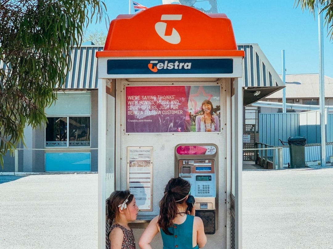 Young girls explore a public telstra payphone. Young girls explore a public telstra payphone.