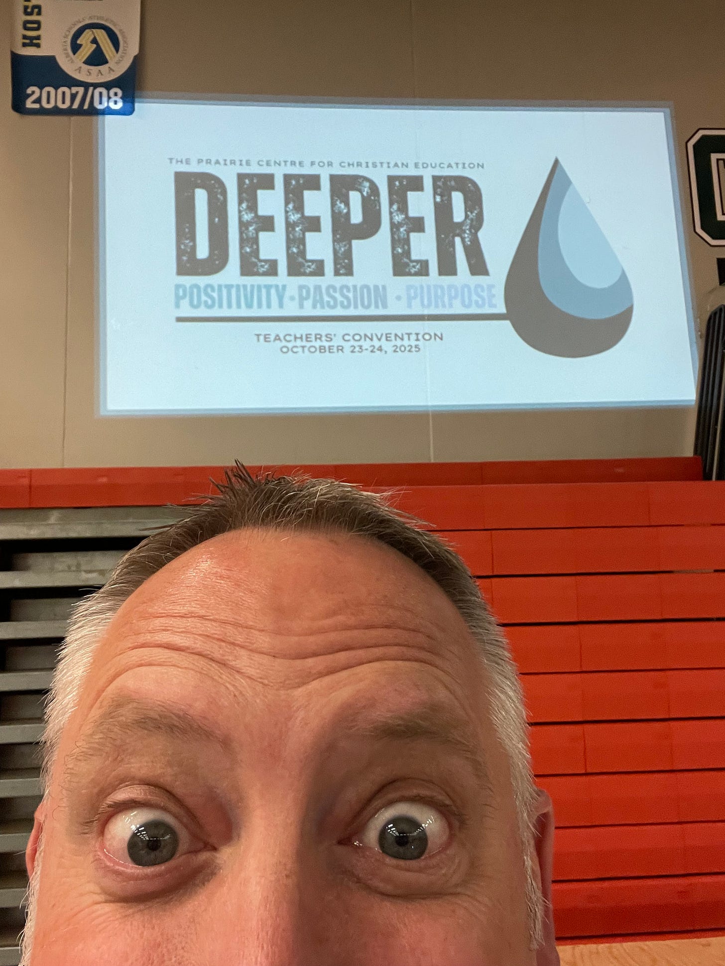 A close up of Dr. Dave's eyes and forehead with the conference theme projected behind him: Deeper: Positivity. Passion. Purpose.