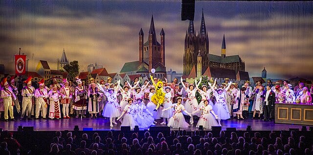 Photo of Opening scene with choir and male ballet from the Divertissementchen 2025 “De kölsche Fledermaus” at the Cologne Opera. (Source: Wikimedia Commons)