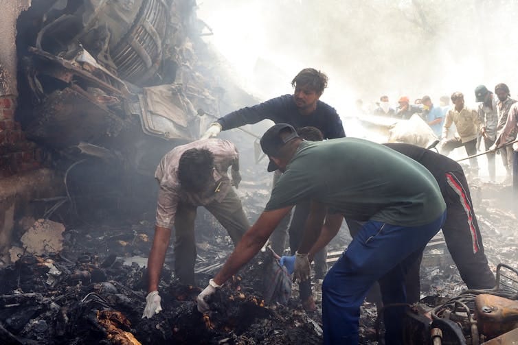 Men picking up wreckage at a crash site. Men picking up wreckage at a crash site.