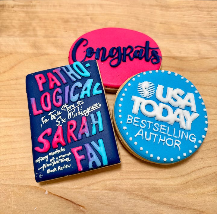 Sarah Fay, delighted, holding Pathological: The True Story of Six Misdiagnosis and the USA Today Best-selling Booklist. We did it! The cookies my team sent me from BBG. Sweets guarding the plate of cookies.