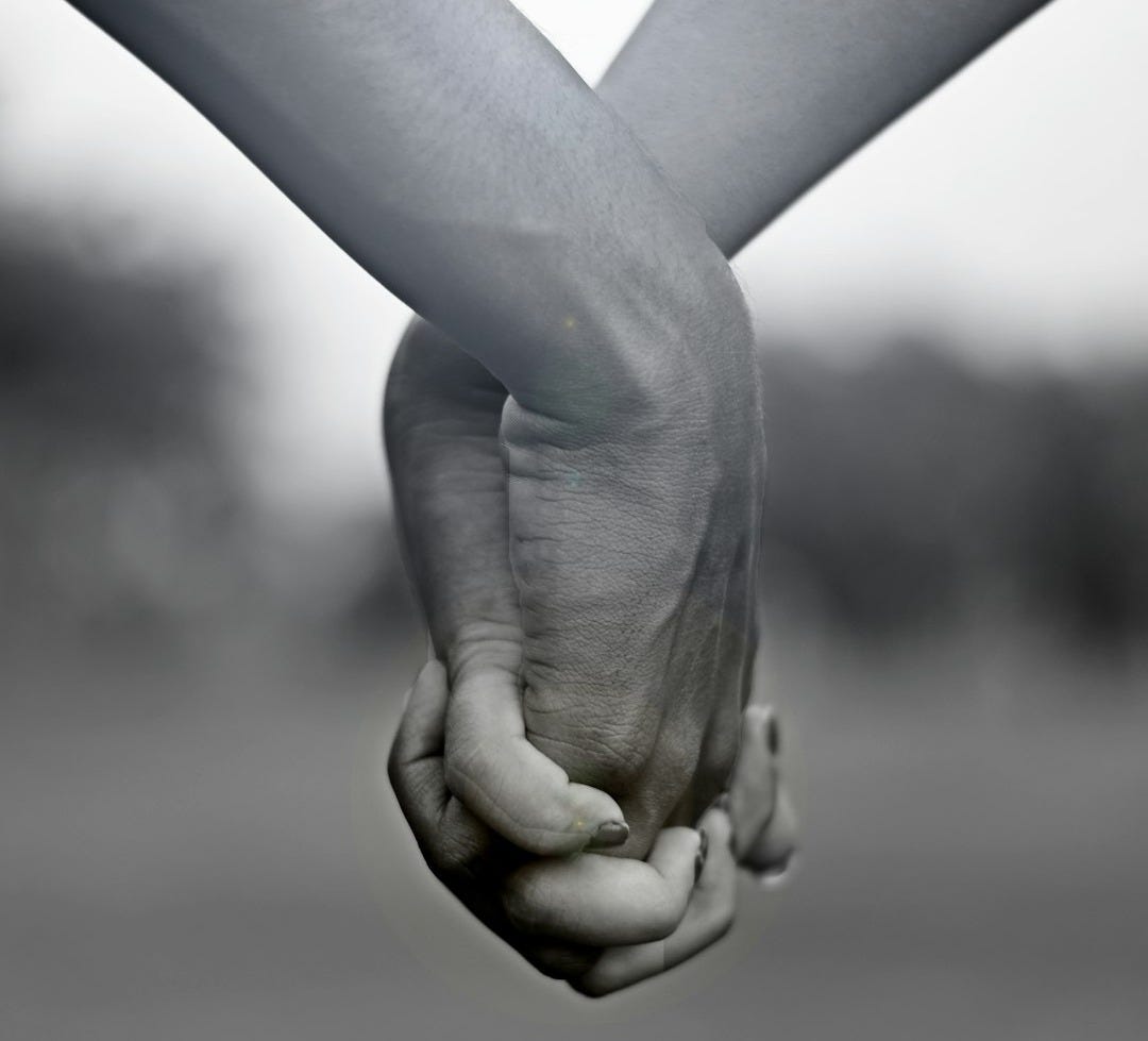grayscale photo of two person holding hands