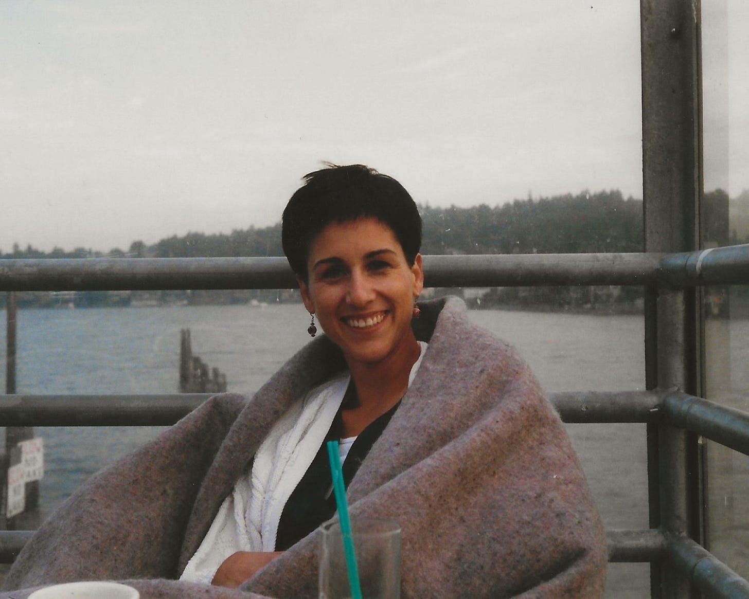 A young woman in her 30s, smiling and relaxed, poses outdoors in warm light. The image, shared by Stephanie Peirolo, was taken around the time of her life-changing naturist trip.