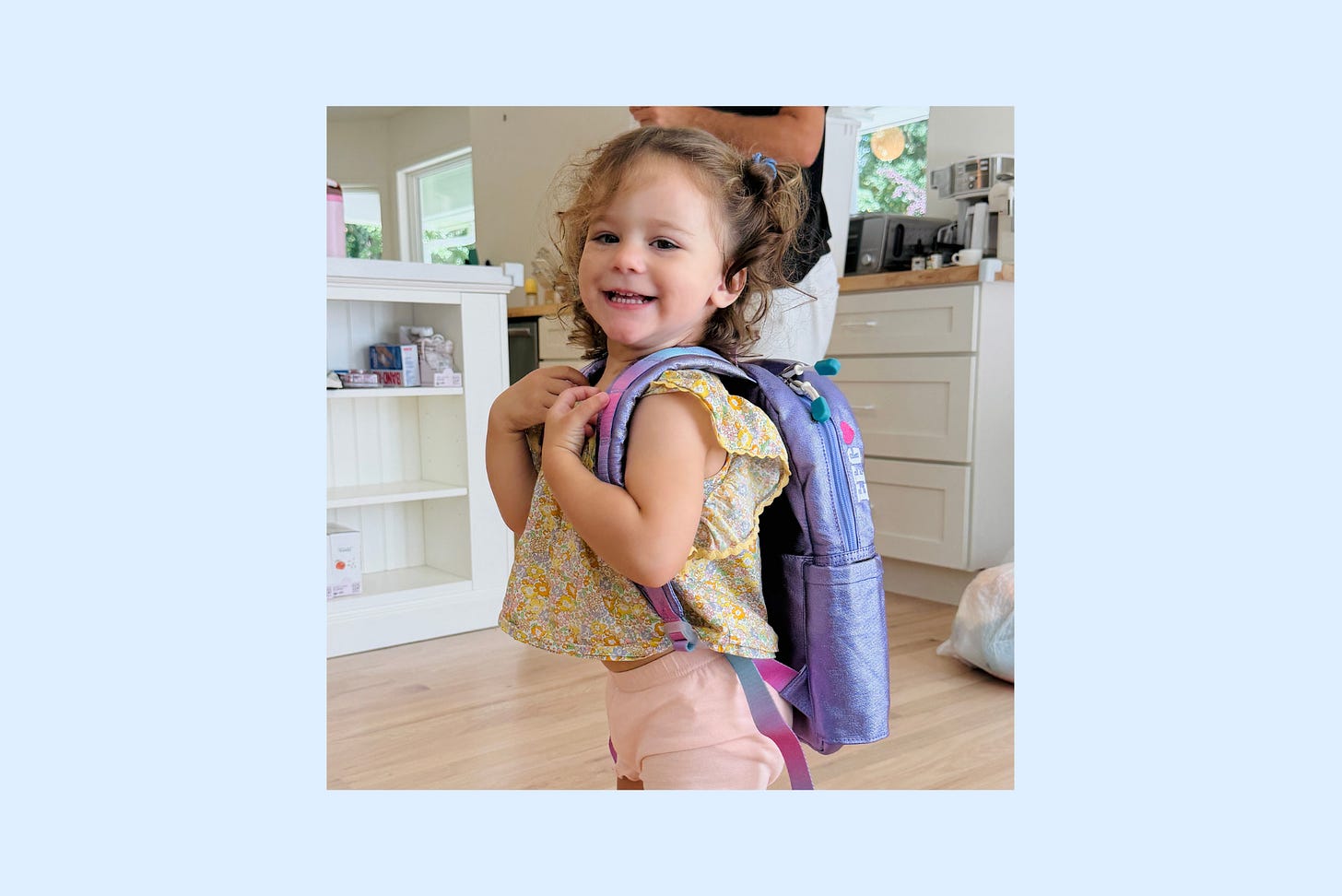 Elodie, two years old, wearing a shiny purple backpack covered in butterflies that is almost as large as she is Elodie, two years old, wearing a shiny purple backpack covered in butterflies that is almost as large as she is
